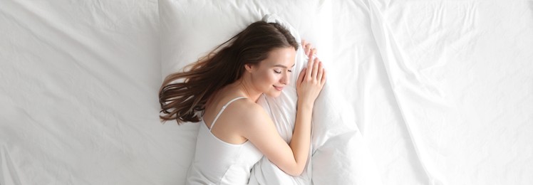 Image of Young woman sleeping on comfortable pillow in bed at home, top view. Banner design