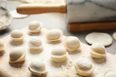 Board with raw dumplings on table, closeup. Process of cooking