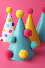 Photo of Beautiful party hats with pompoms on pink background