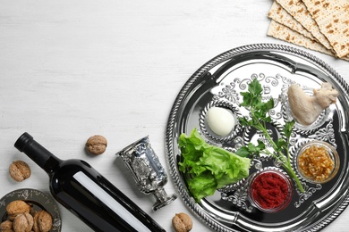 Photo of Flat lay composition with symbolic Passover (Pesach) items and meal on wooden background, space for text
