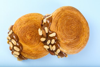 Supreme croissants with chocolate paste and nuts on light blue background, above view. Tasty puff pastry