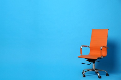 Comfortable office chair on light blue background, space for text