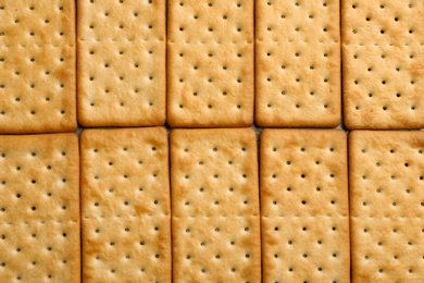 Many delicious crackers as background, top view