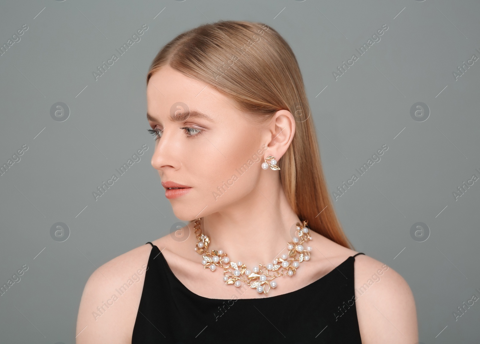 Photo of Beautiful young woman with elegant jewelry on gray background