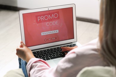 Photo of Woman with laptop activating promo code while doing online shopping indoors, closeup
