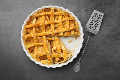 Photo of Tasty homemade quince pie with cake server on grey table, flat lay