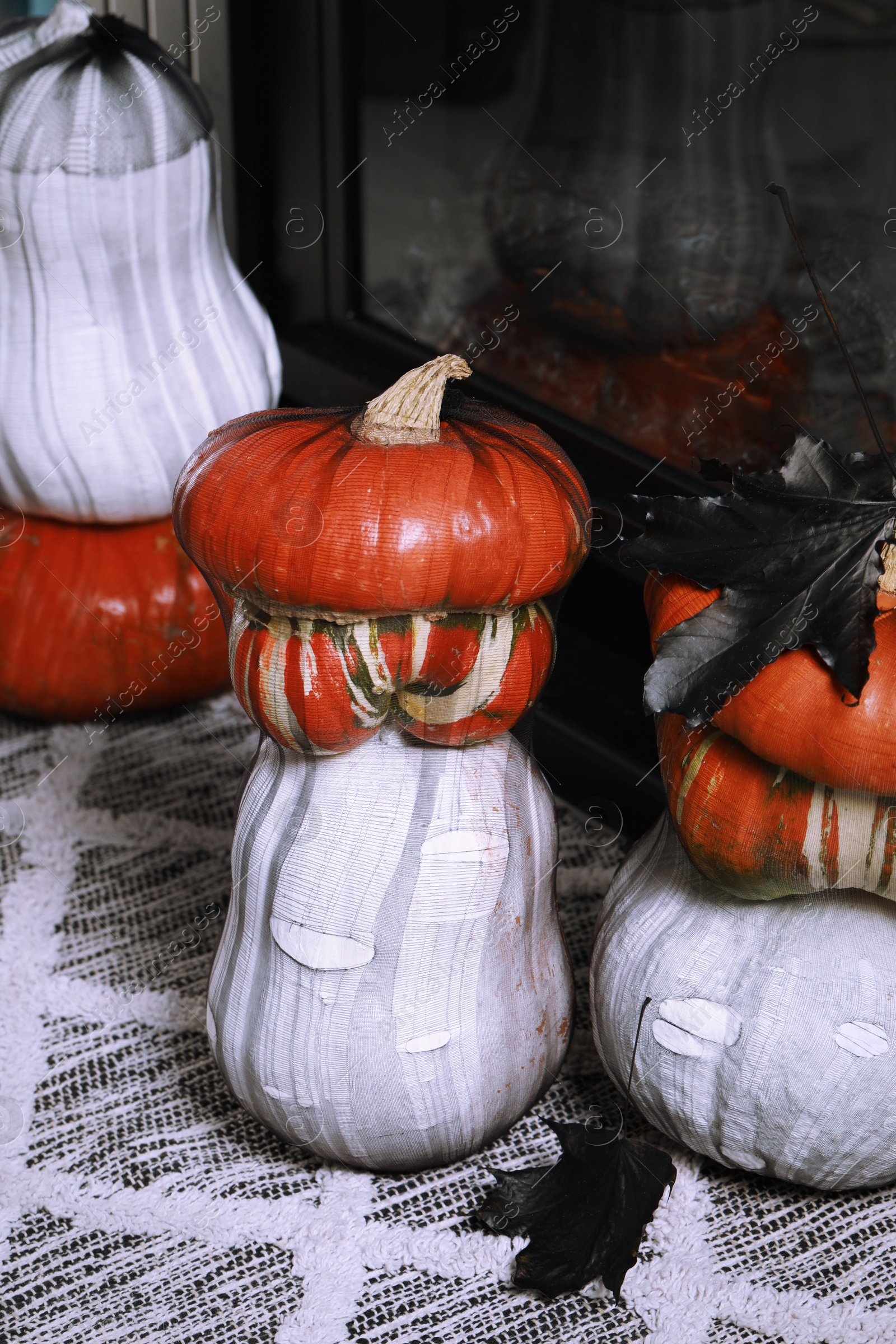 Photo of Colorful pumpkins on rug near fireplace. Halloween decorations