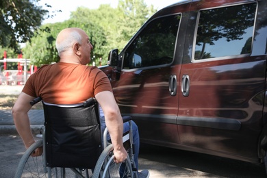 Photo of Senior man in wheelchair near van outdoors