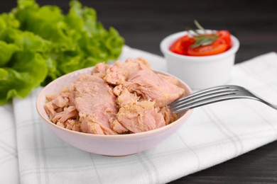 Bowl with canned tuna and fork on table, closeup