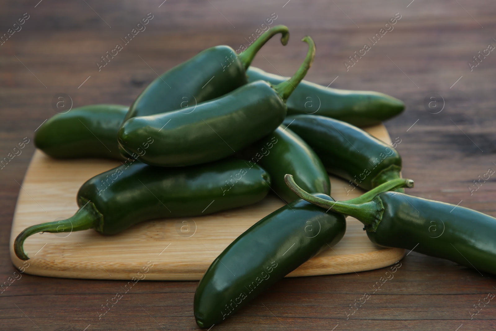 Photo of Fresh green jalapeno peppers on wooden table, closeup