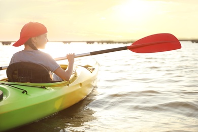 Little girl kayaking on river, back view. Summer camp activity