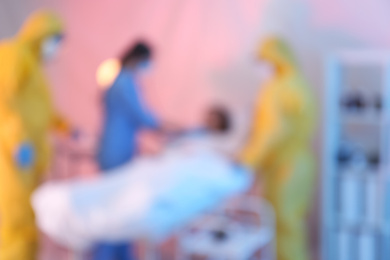 Photo of Blurred view of professional paramedics examining patient with virus in quarantine ward