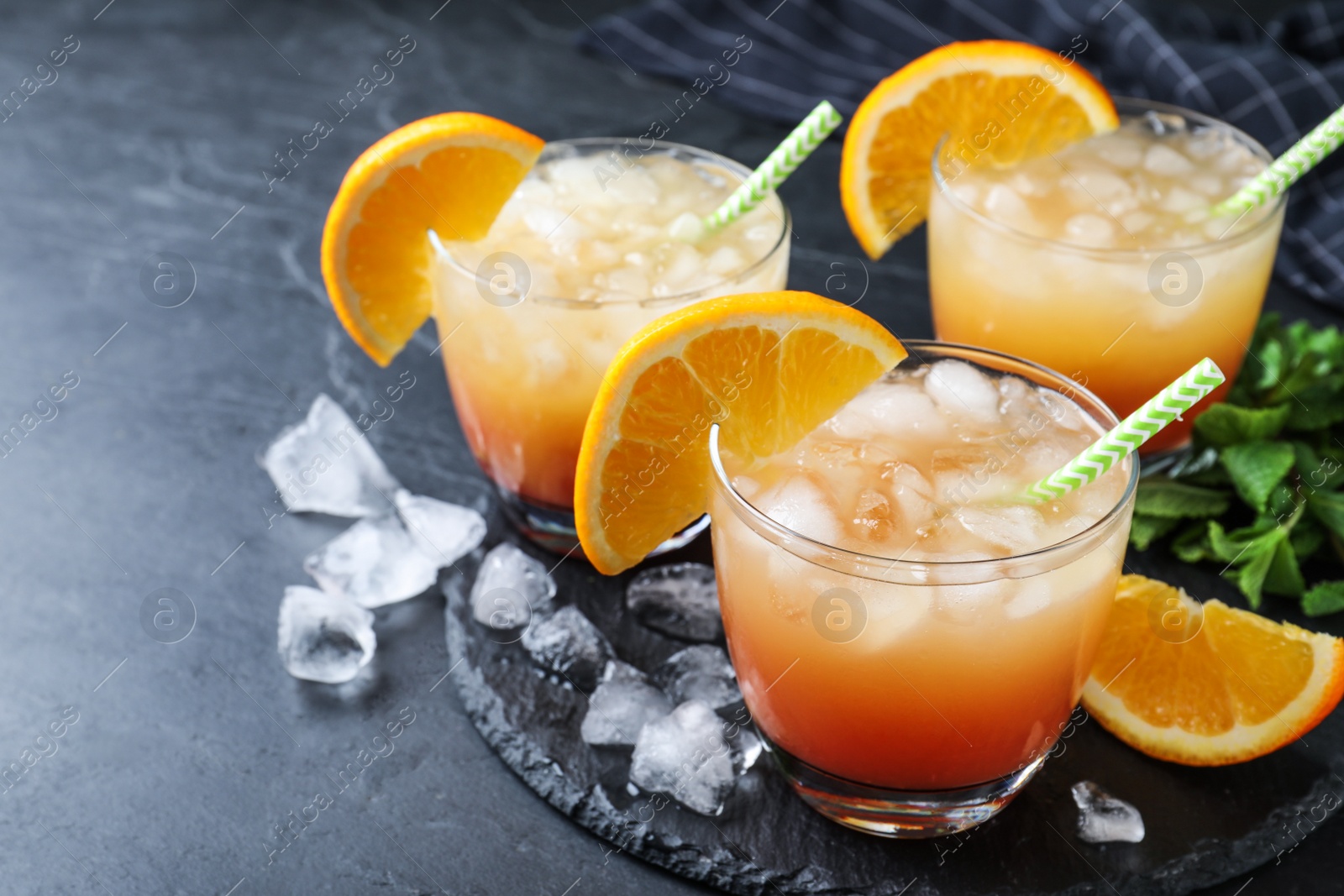 Photo of Glasses of tasty tropical cocktail on black table