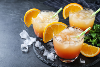 Glasses of tasty tropical cocktail on black table