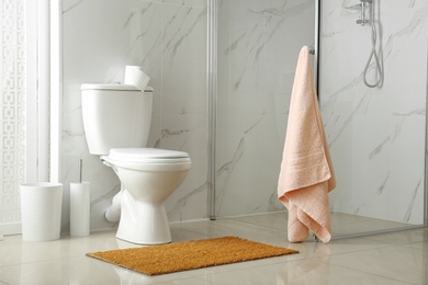 Toilet bowl near shower stall in modern bathroom interior