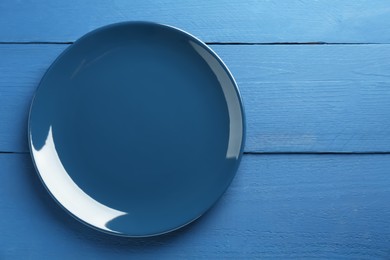 Beautiful ceramic plate on blue wooden table, top view. Space for text