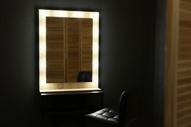 Photo of Beautiful mirror with light bulbs and chair in makeup room