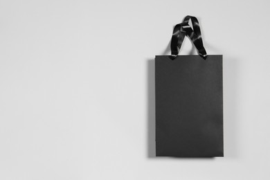 One black paper shopping bag on grey background, top view. Space for text
