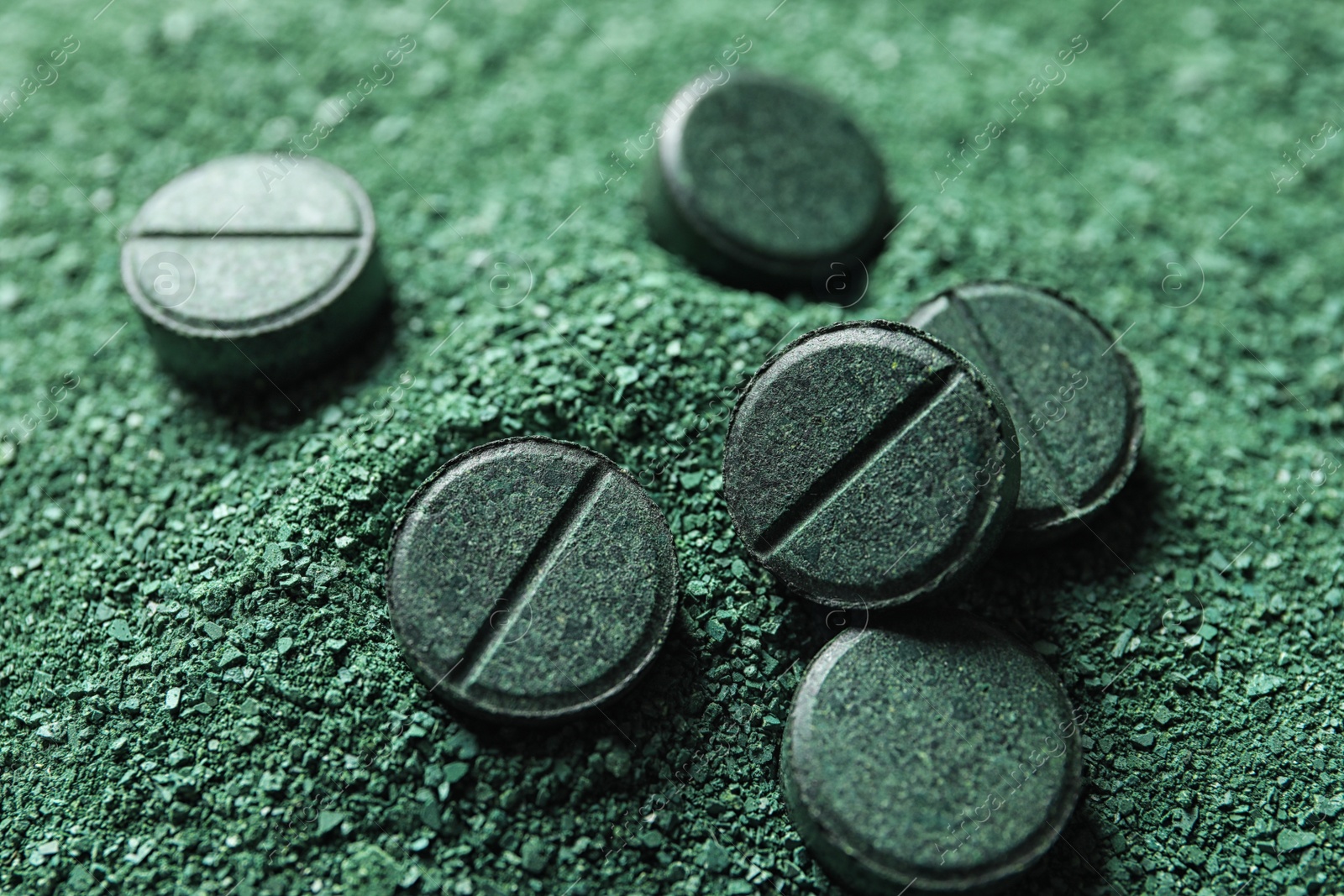 Photo of Natural green spirulina powder and pills as background, closeup