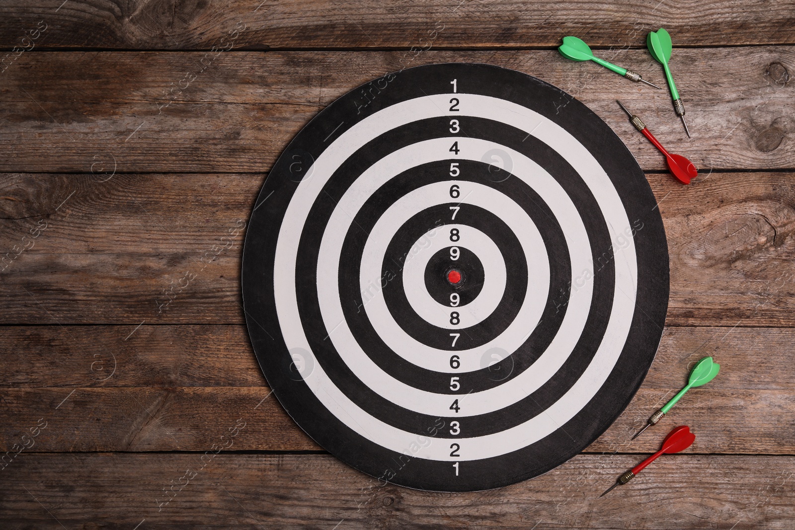 Photo of Dart board with color arrows on wooden background, top view. Space for text