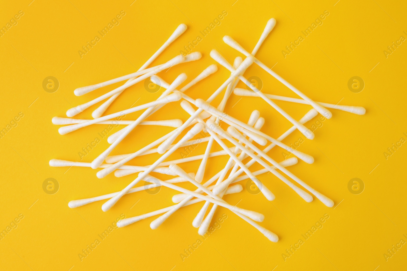 Photo of Many clean cotton buds on yellow background, flat lay