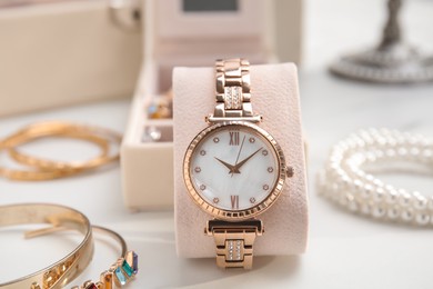 Photo of Elegant watch and bijouterie on white marble table