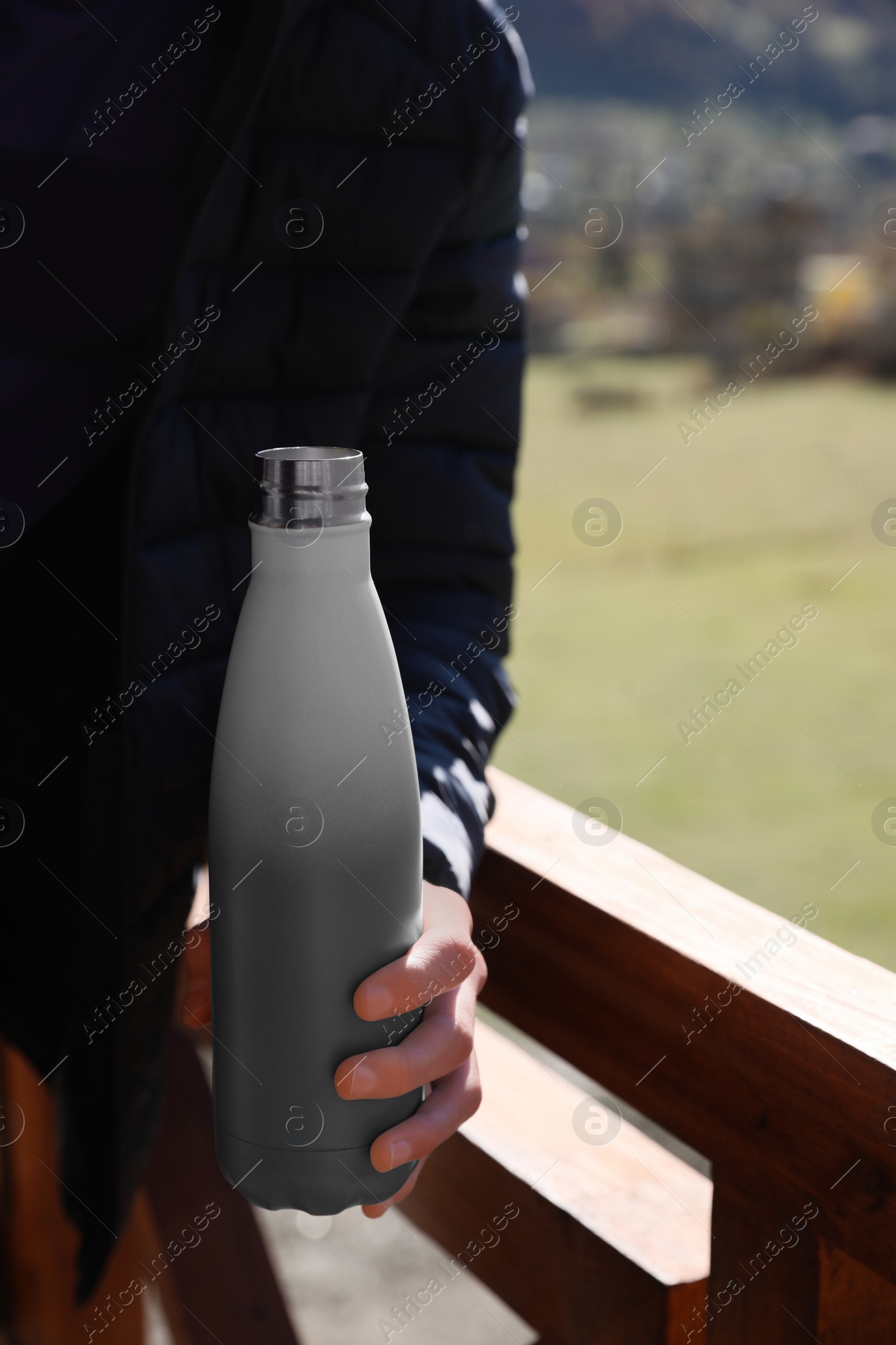 Photo of Boy holding thermo bottle with drink in mountains on sunny day, closeup