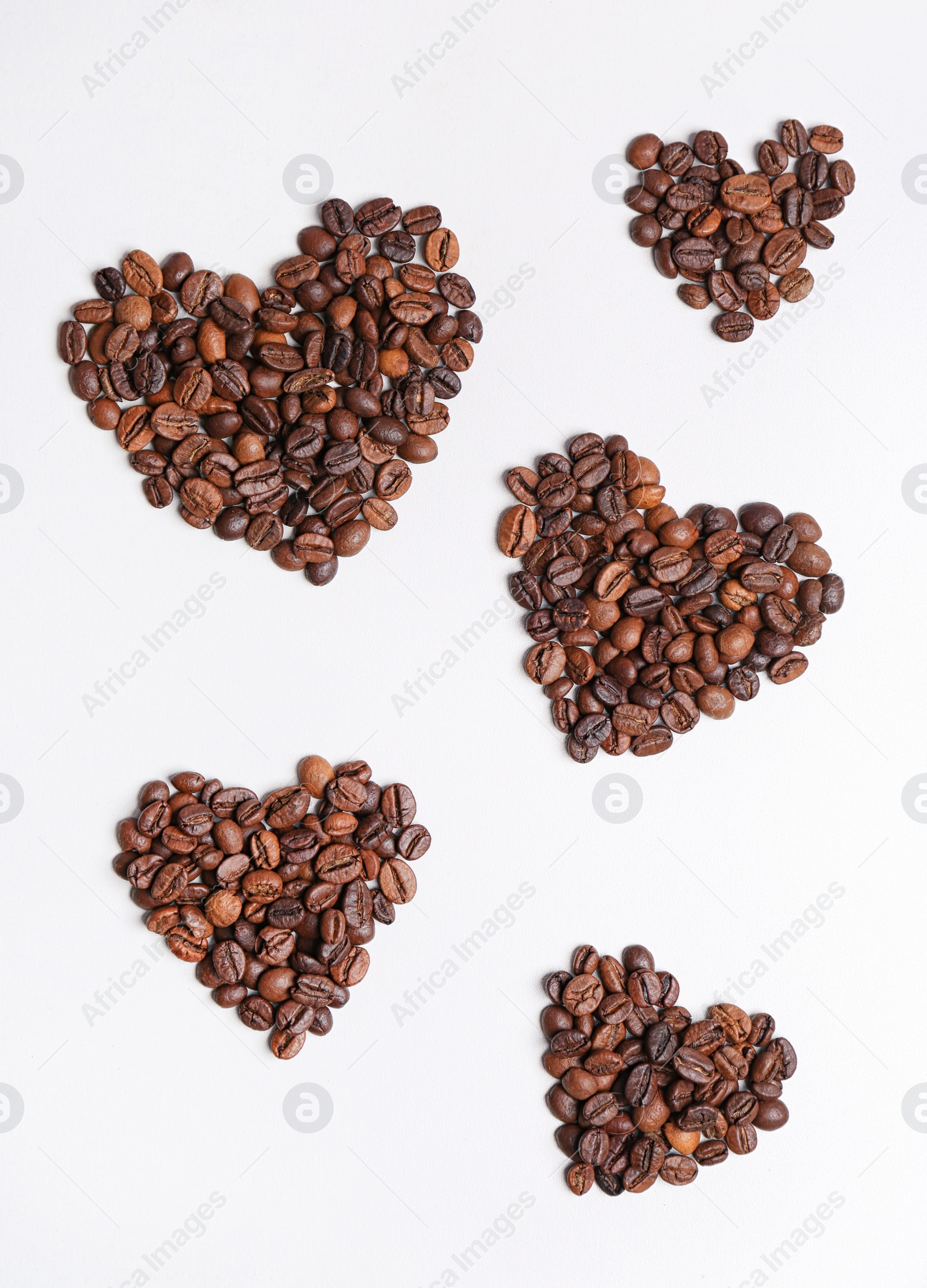 Photo of Hearts made of roasted coffee beans on white background