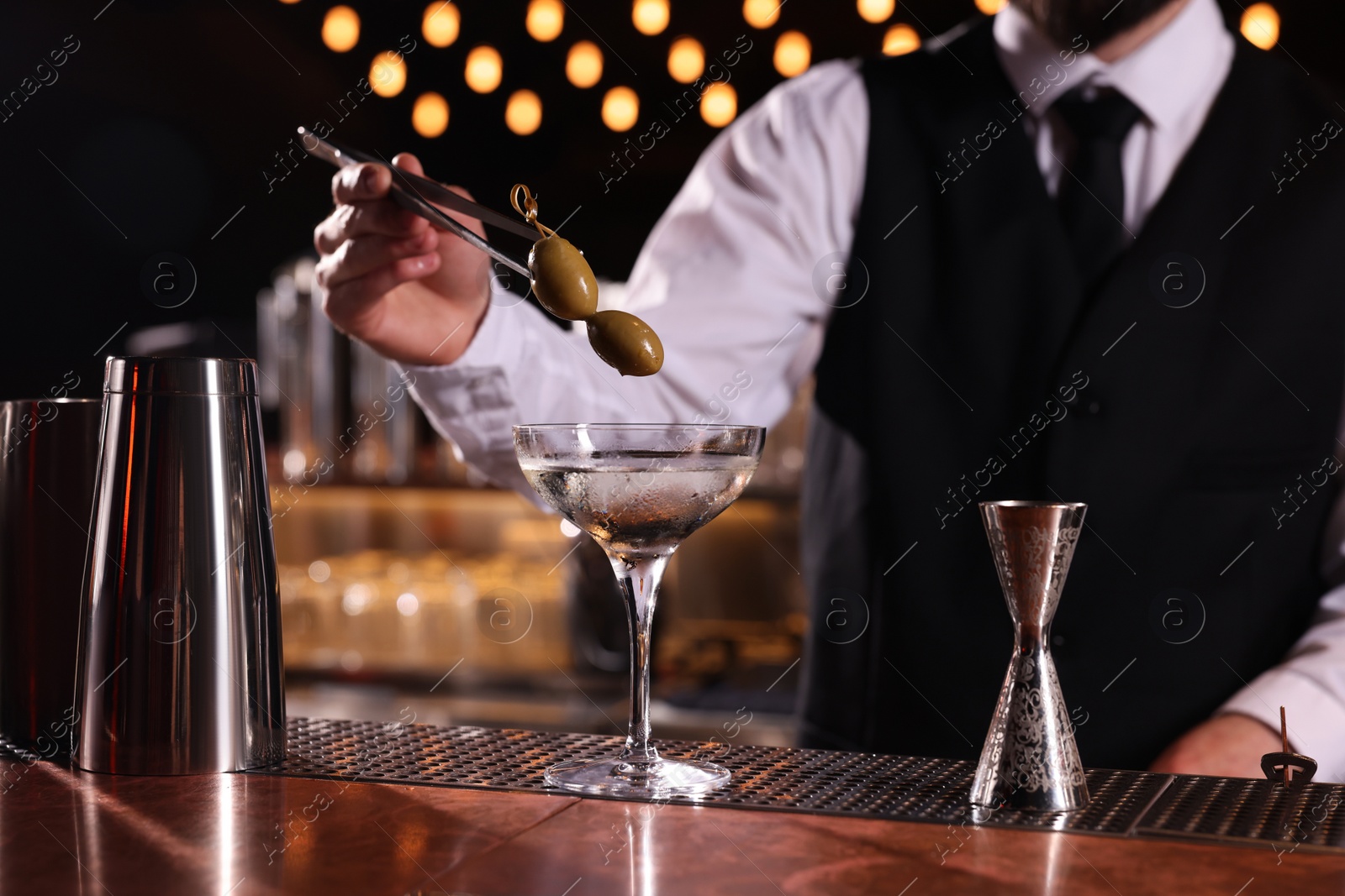 Photo of Bartender preparing fresh Martini cocktail at bar counter, closeup