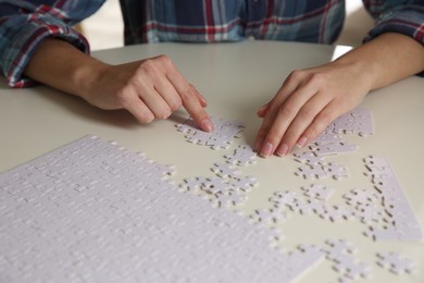 Young woman playing with puzzles at table, closeup