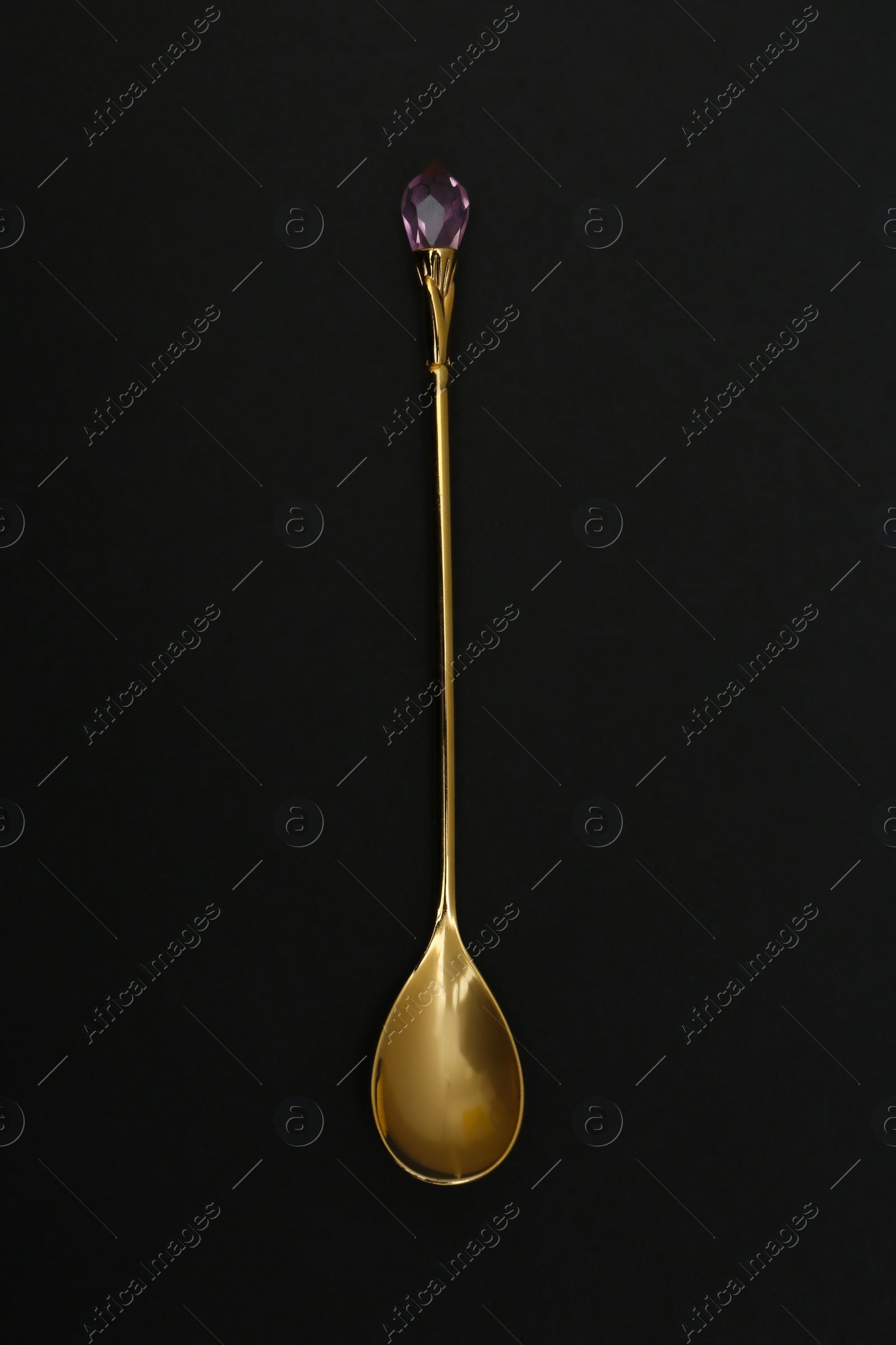 Photo of Shiny gold spoon on black background, top view