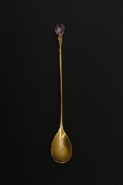 Photo of Shiny gold spoon on black background, top view