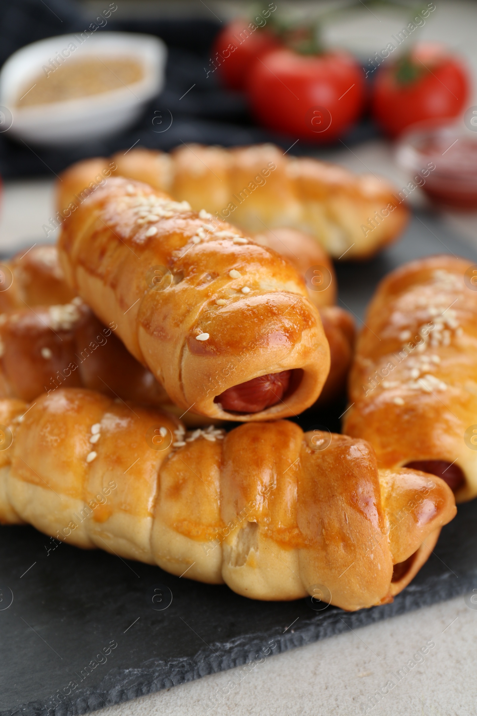 Photo of Delicious sausage rolls and ingredients on beige table, closeup