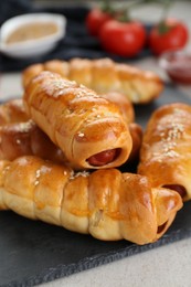 Photo of Delicious sausage rolls and ingredients on beige table, closeup