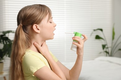 Photo of Little girl using throat spray at home. Space for text