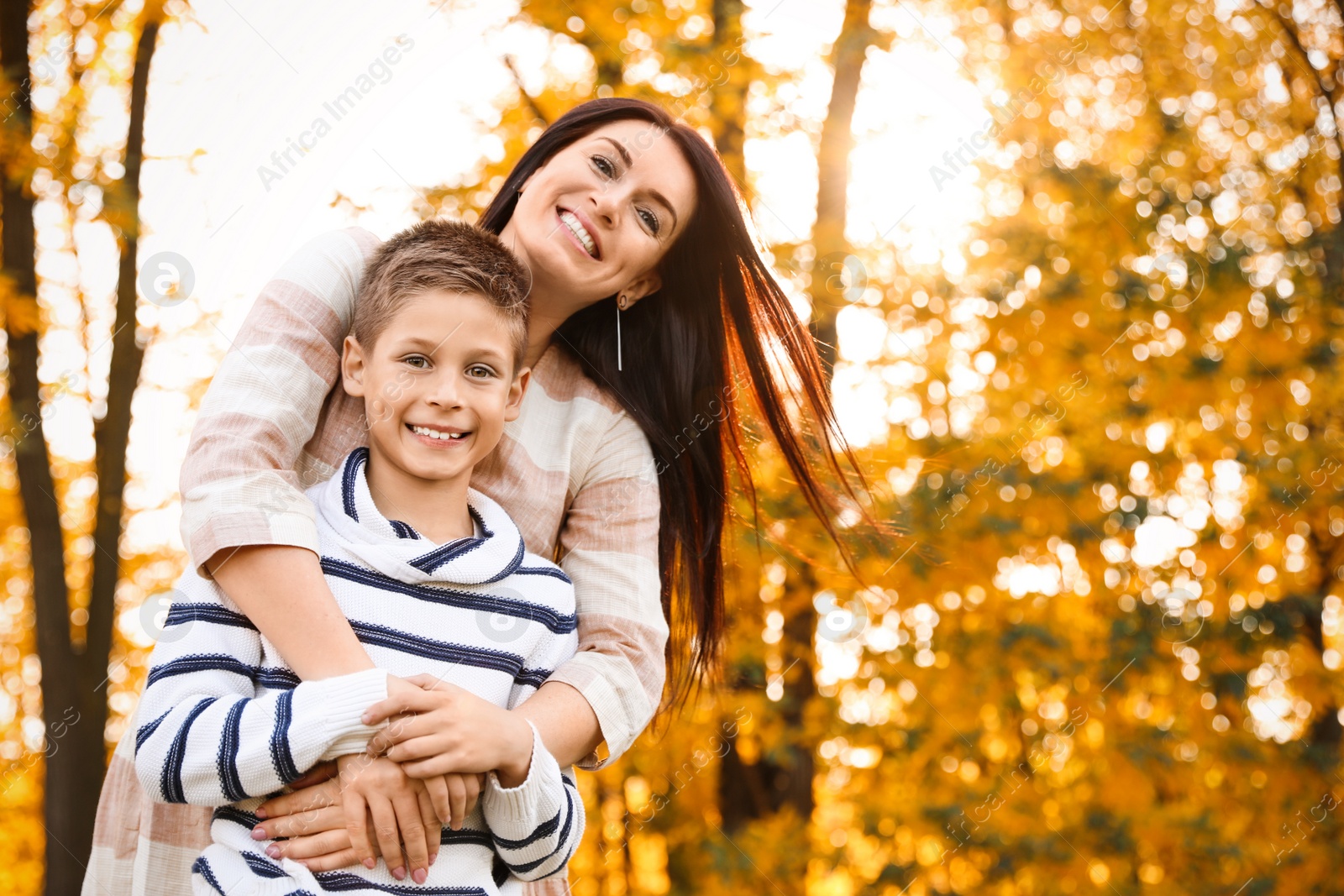 Photo of Happy mother with son in sunny park. Autumn walk