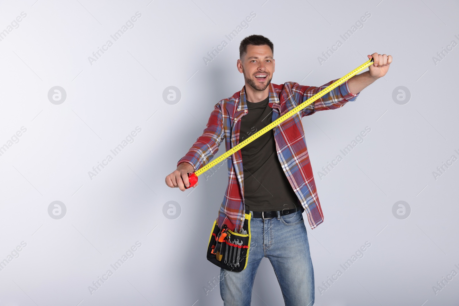Photo of Handsome worker with measuring tape on white background, space for text