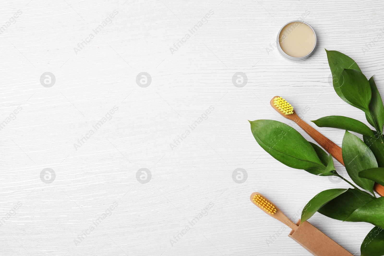 Photo of Flat lay composition with bamboo toothbrushes and space for text on white wooden background