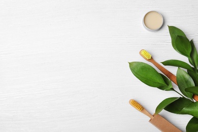 Flat lay composition with bamboo toothbrushes and space for text on white wooden background