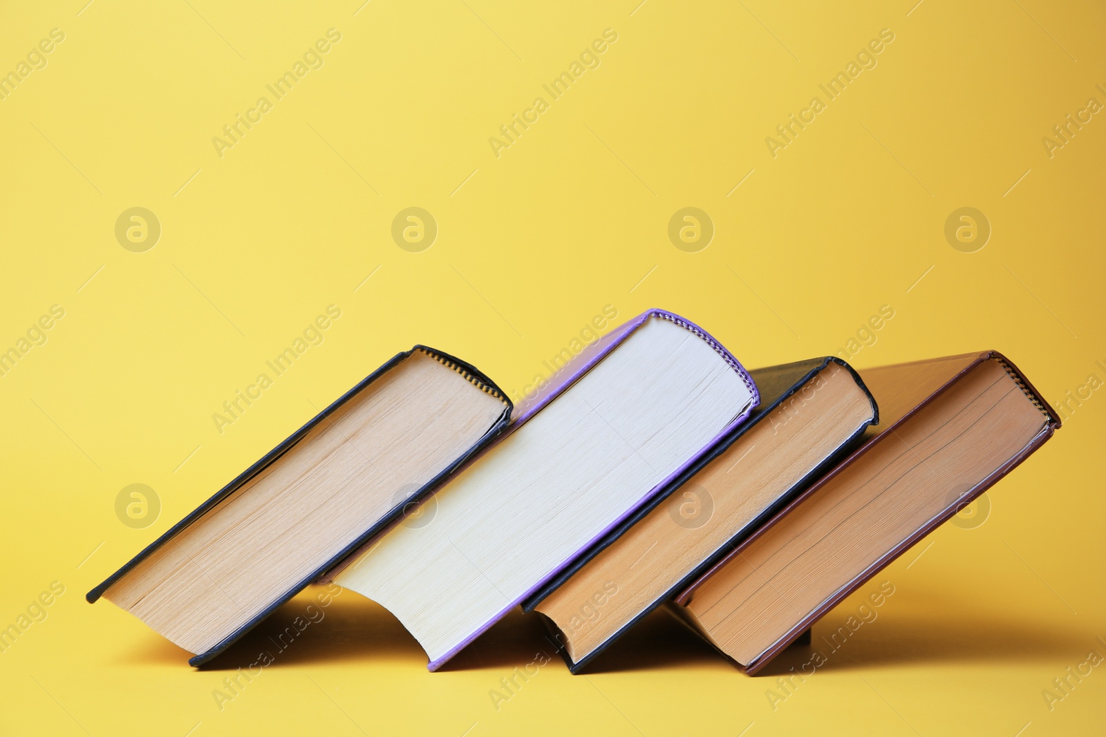 Photo of Collection of hardcover books on yellow background, space for text