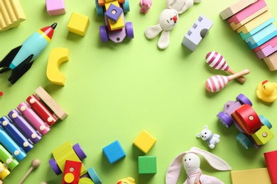 Photo of Frame made of different toys on green background, flat lay. Space for text