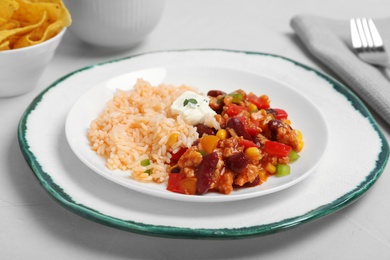 Chili con carne served with rice and sauce on table