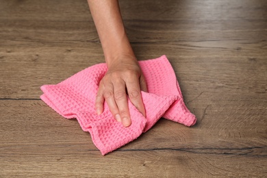 Photo of Woman wiping wooden table with kitchen towel, closeup