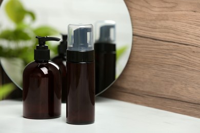 Photo of Different face cleansing products near mirror on white table. Space for text