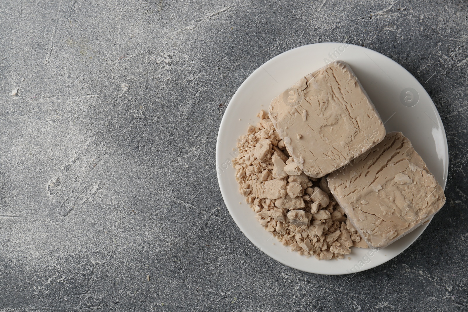 Photo of Compressed yeast on grey table, top view. Space for text