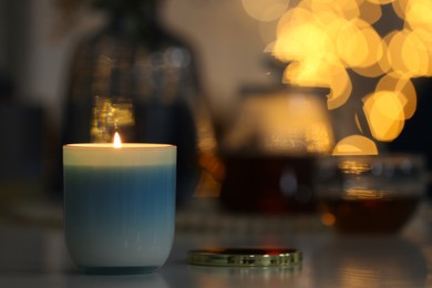 Photo of Burning candle on table, space for text. Bokeh effect
