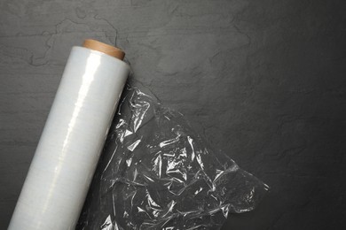Photo of Roll of plastic stretch wrap film on black table, top view. Space for text