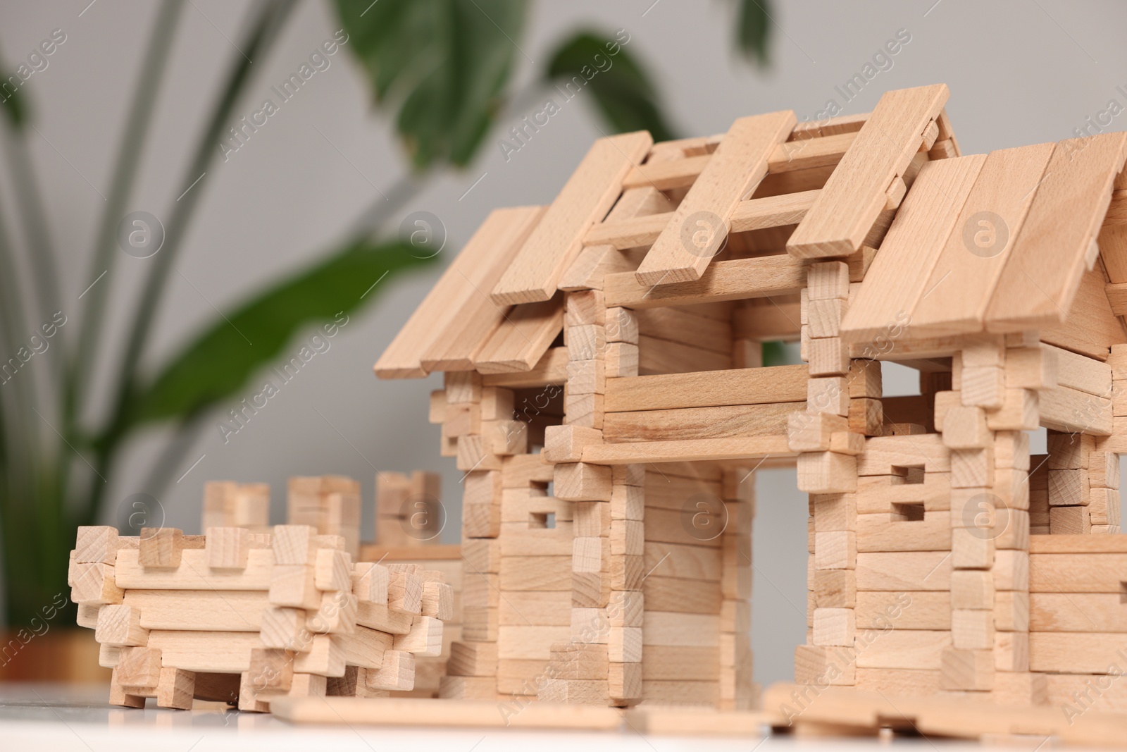 Photo of Wooden entry gate on white table against blurred background, closeup. Children's toy