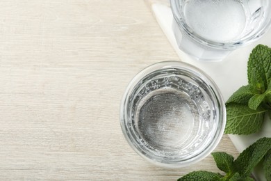 Photo of Glasses of soda water and mint on white wooden table, flat lay. Space for text
