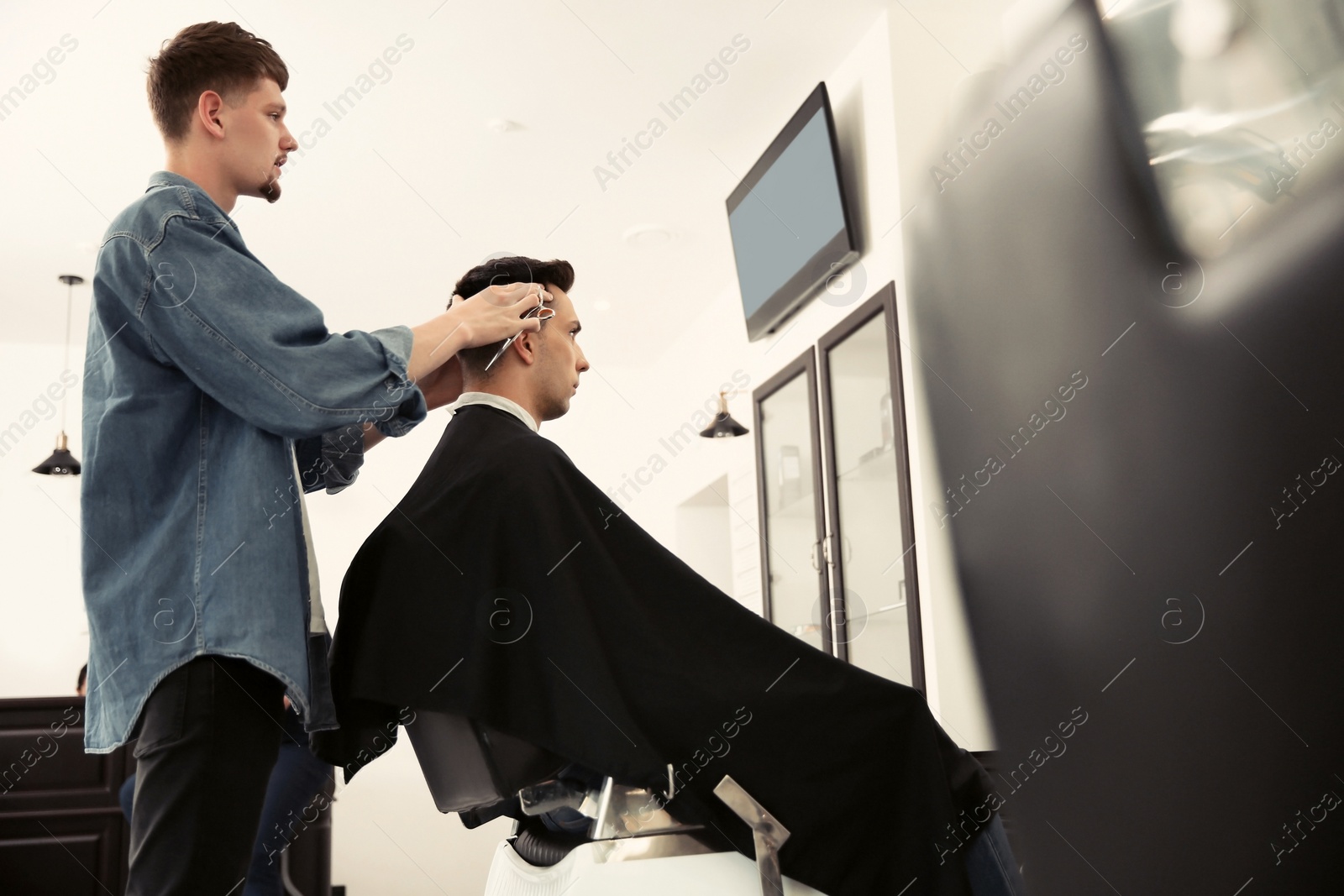 Photo of Professional barber working with client in hairdressing salon. Hipster fashion